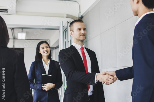 Manager, businessman, Europe investor or boss shake hand  with Asian Entrepreneur and  successful  big project deal in meeting  by interpreter standing near to translate photo