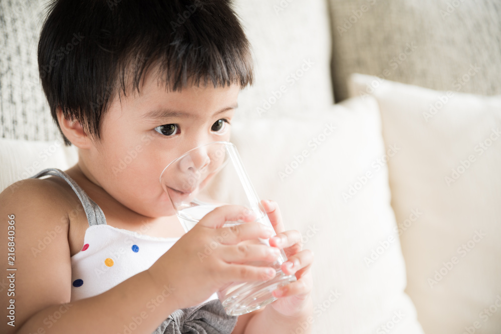 Cute little girl drinking water on sofa at home. health care concept. Cute little girl drinking water on sofa at home. health care concept.