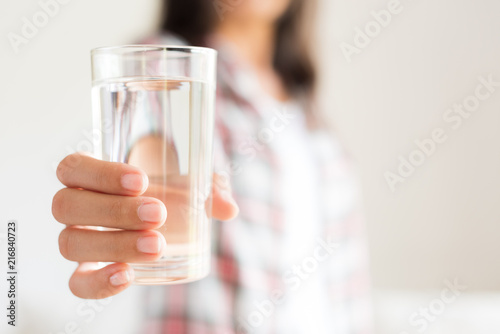 Happy beautiful young woman holding drinking water glass in her hand. Health care concept.