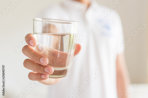 A glass of clean mineral water in man's hands. Concept of environment protection, healthy drink.