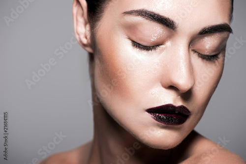 fashionable girl with black lips and wet face  isolated on grey