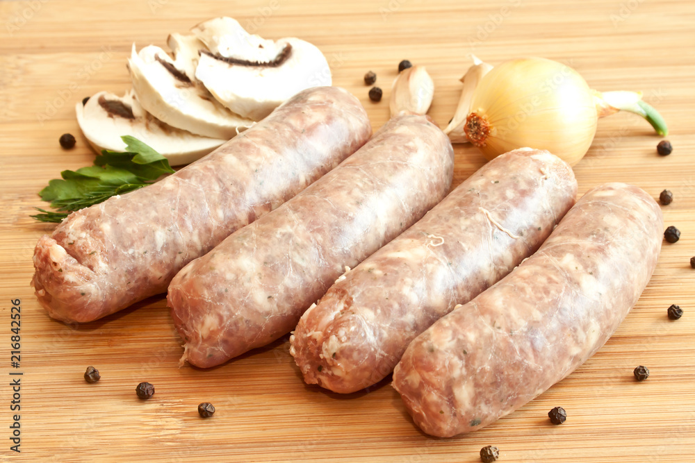 Uncooked sausages with vegetables on the chopping board Uncooked sausages with vegetables on the chopping board