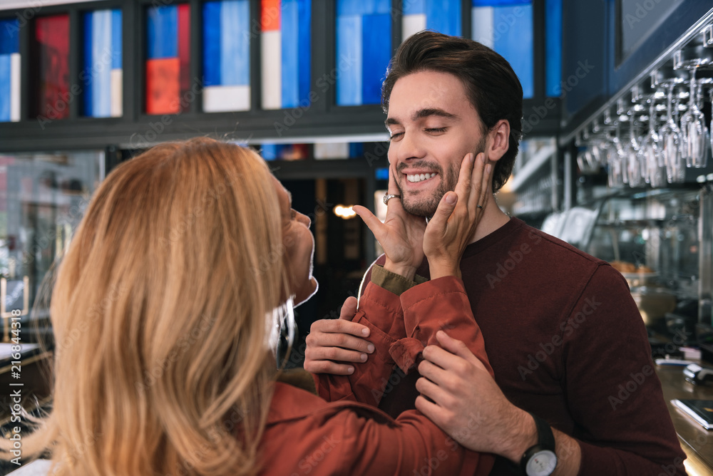 Most handsome face. Woman touching satisfied cheerful man who taking ...