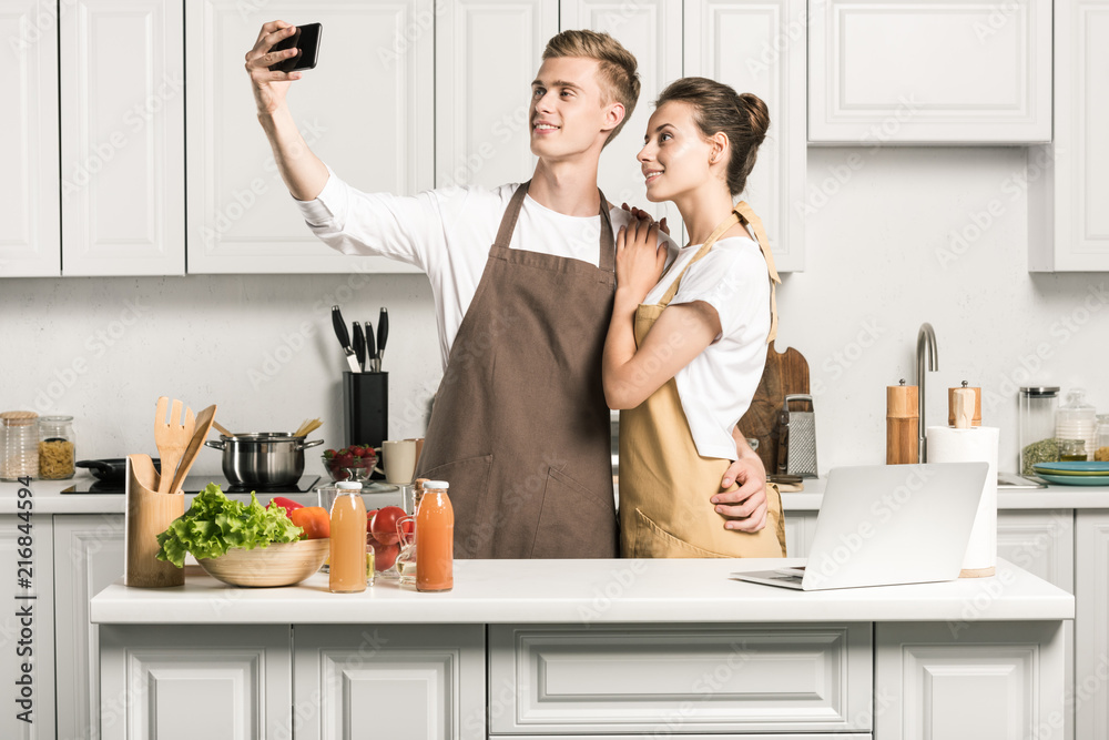 young couple taking selfie with smartphone in kitchen