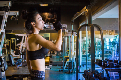 Asian woman drinking water after exercising in gym.Instagram style filter photo vintage tone
