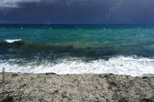Fototapeta Naklejka Na Ścianę i Meble -  Small waves with foam at the time of storm beginning in the evening on the shore of the dark sea on the beach of the sea resort