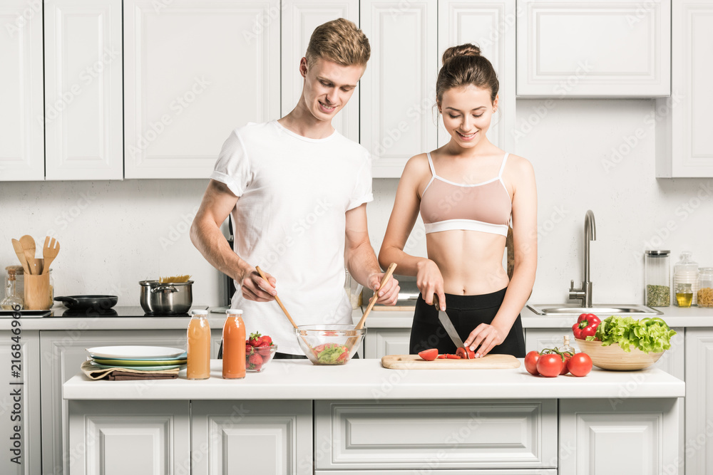 young couple cooking salad together in kitchen young couple cooking salad together in kitchen