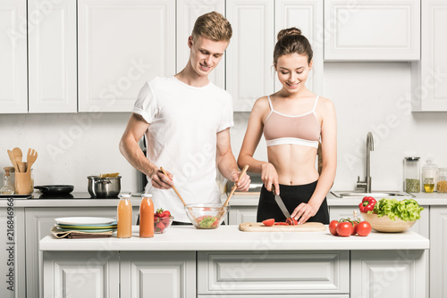 young couple cooking salad together in kitchen