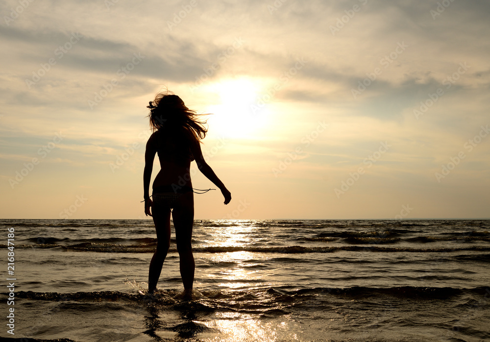 Silhouette of a young woman in sea at sunset.
