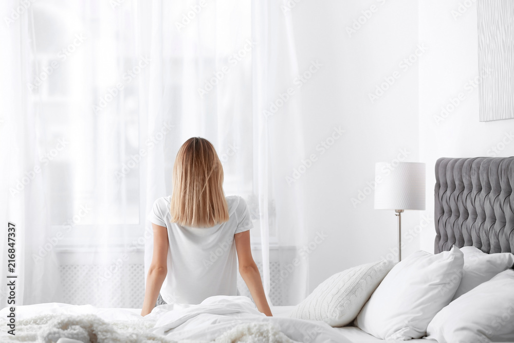 Young beautiful woman sitting on bed after sleeping at home Young beautiful woman sitting on bed after sleeping at home