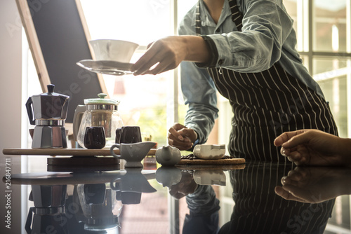 barista man holding cup of hot coffee to drink in cafeteria with copy space for text on advertisement board