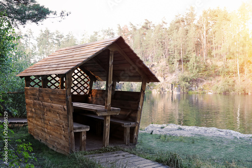 Wooden gazebo near lake. Camping season