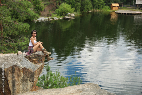 Young woman on rocky mountain near lake. Camping season