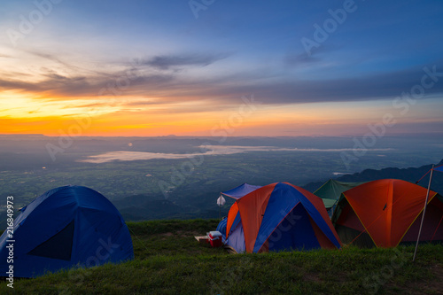 view of tourist tent on green meadow at sunrise. Adventure travel active lifestyle. Camping in the mountains. Tents against the beautiful mountains.
