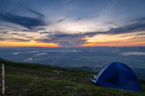 Tents on top of the hillside near the peak of mountain range at sunrise.Tourist camping tents at national park in the morning time. mountain landscape. © Satawat