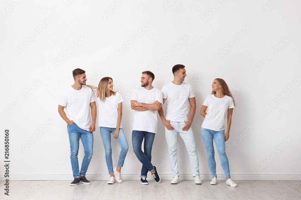 Group of young people in jeans near light wall Group of young people in jeans near light wall