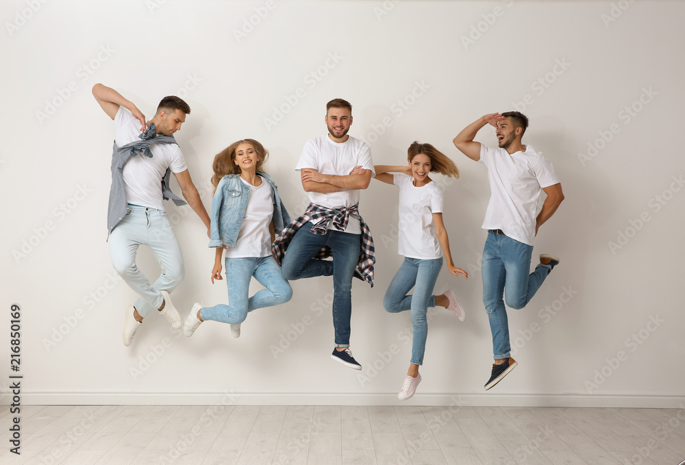 Obraz premium Group of young people in jeans jumping near light wall