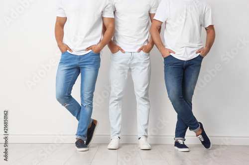 Group of young men in jeans near light wall