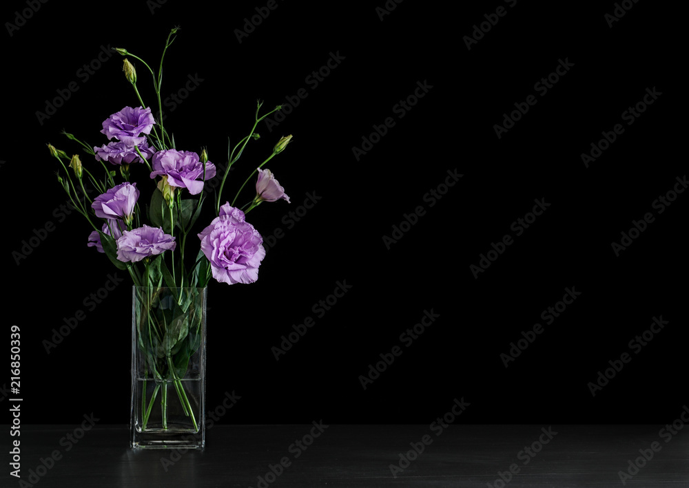 Vase with beautiful Eustoma flowers on table against dark background Vase with beautiful Eustoma flowers on table against dark background