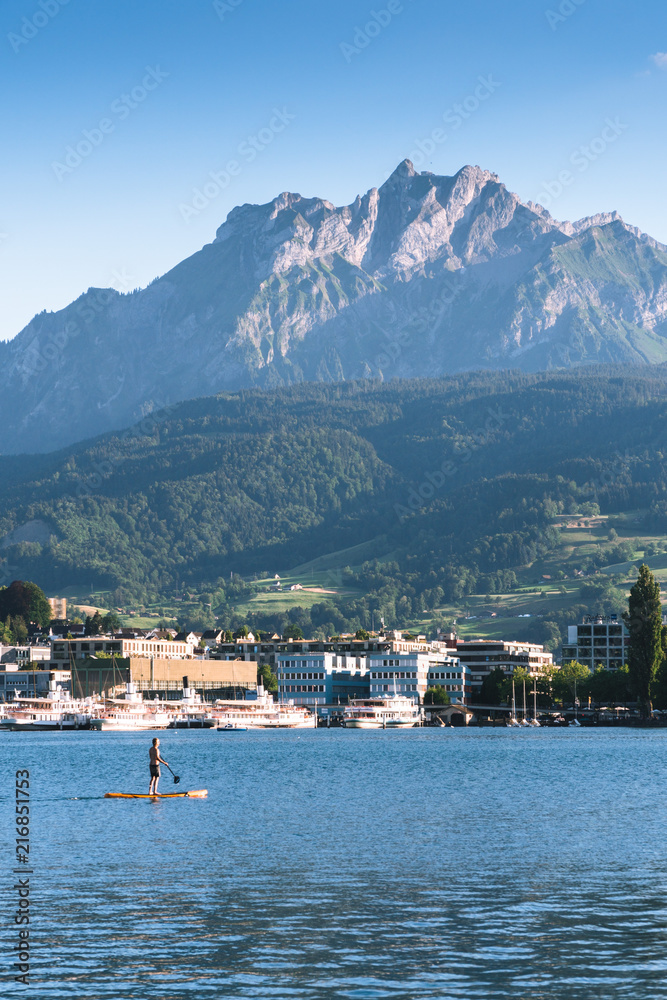 man are doing yoga on a stand up paddle board SUP on a beautiful Lake Lucerne, Pilatus mountain the summer season, boats and ships, travel and vacation to Europe concept, Luzern, Switzerland