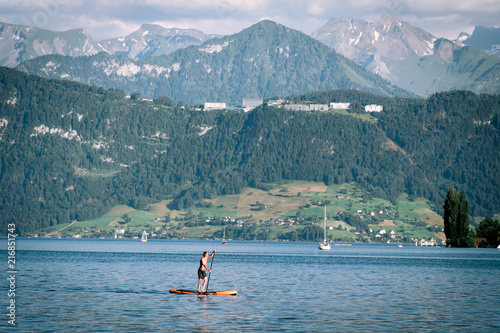 man a stand up paddle board SUP view of Lake Lucerne, the summer season, boats and ships, travel and vacation to Europe concept, Luzern, Switzerland