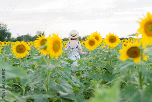 Young woman in straw hat in the sunflower field