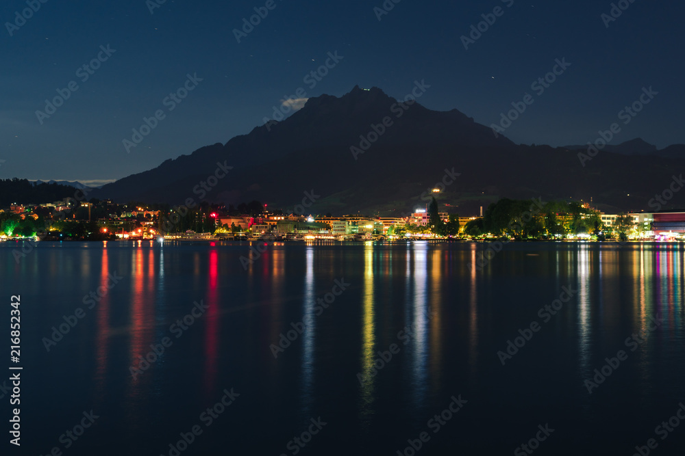 Night summer view on Alps mountains lake and Pilatus mountain, city glows, travel and vacation in Europe, embankment, Luzern, Switzerland