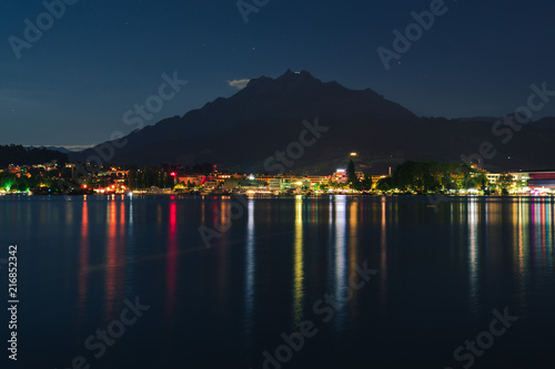 Night summer view on Alps mountains lake and Pilatus mountain, city glows, travel and vacation in Europe, embankment, Luzern, Switzerland