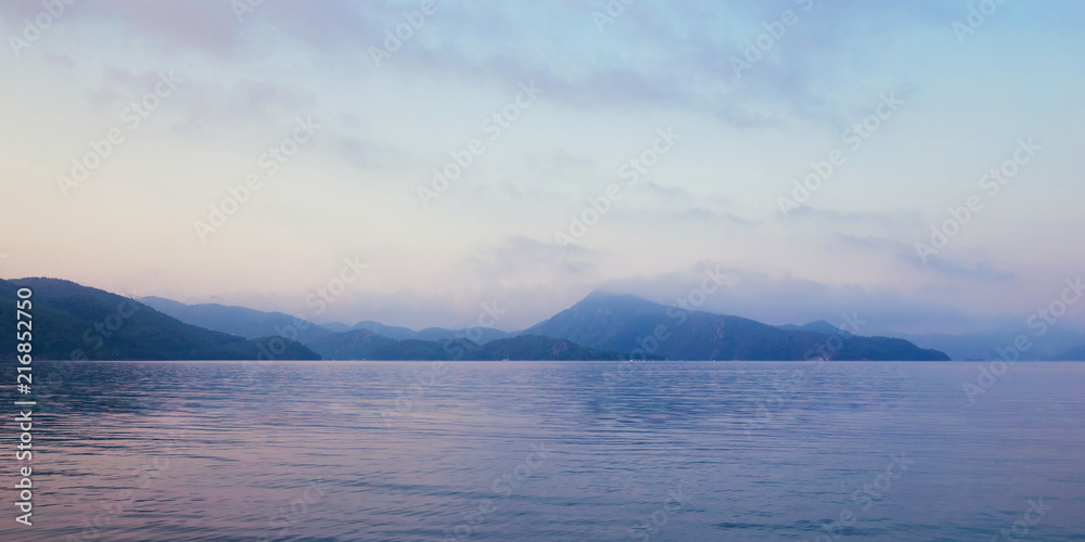 Sunrise in bay of sea. Morning haze, beautiful view on mountains and sea.