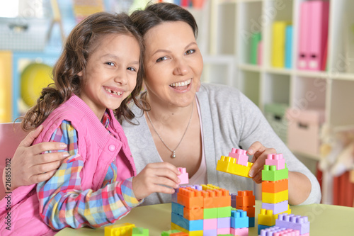 little girl and her mother playing with colorful plastic blocks