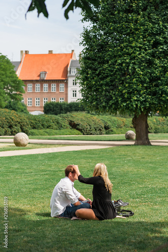 Young couple having a relaxing date in a Danish park. Traditional architecture of Old Town of Copenhagen, Denmark. Concept of hygge.