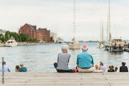 Senior couple enjoying a relaxing summer day in the Copenhagen port with boats and yachts in the Old Town. Concept of hygge.