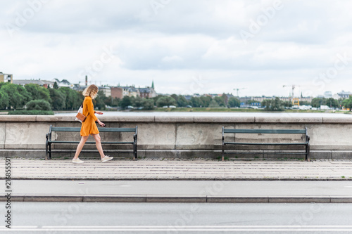 Young fashionable woman walking on the Queen Louise Bridge over Peblinge So. Traditional danish architecture of Copenhagen, Denmark