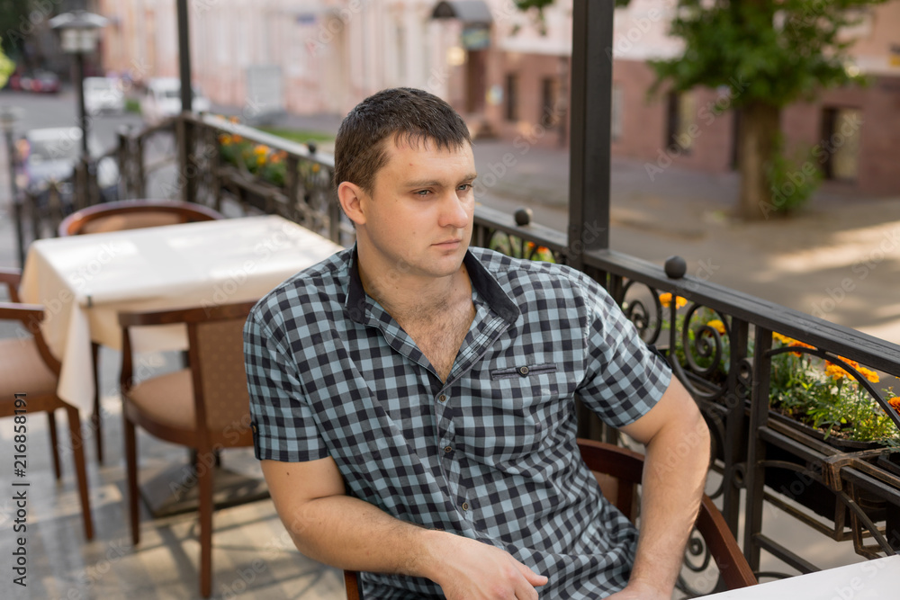 young man. the man in the shirt in the cage. portrait of a man. a man at a table in a cafe in the open area. young man. the man in the shirt in the cage. portrait of a man. a man at a table in a cafe in the open area.