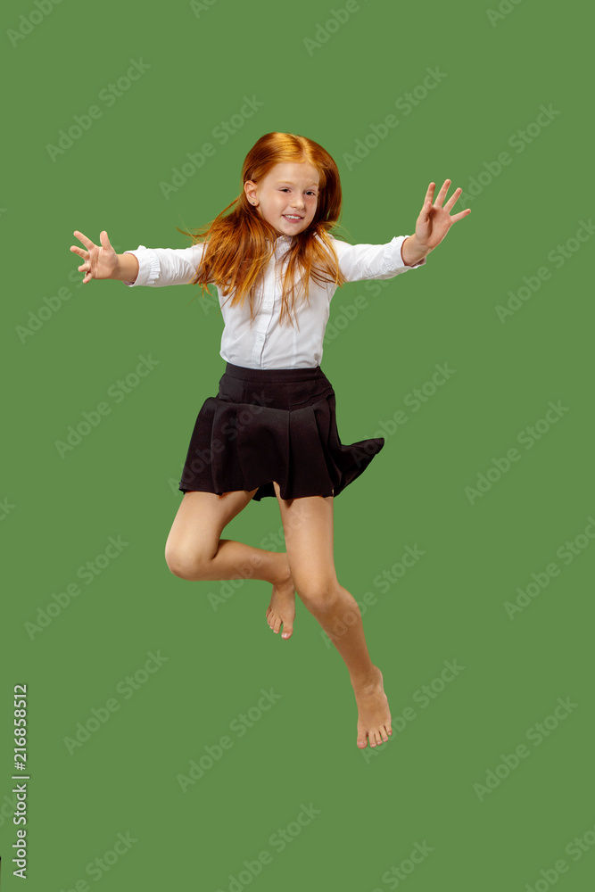 Young happy caucasian teen girl jumping in the air, isolated on green studio background. Beautiful female half-length portrait. Human emotions, facial expression concept. Young happy caucasian teen girl jumping in the air, isolated on green studio background. Beautiful female half-length portrait. Human emotions, facial expression concept.