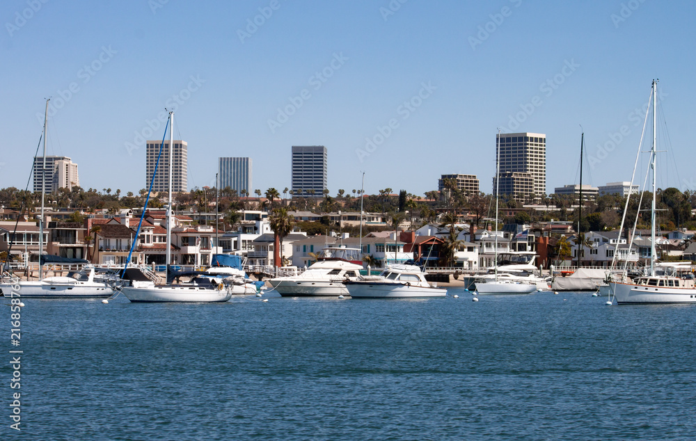 Newport Beach Harbor in California city skyline with boats homes and Fashion Island high rise buildings in the background