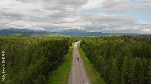 Aerial footage of a road through forest and mountain landscape in Northern Sweden with mountain Åreskutan visible in the background. photo