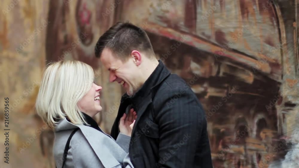 couple in love smiling, laughing and hugging near the brown wall in autumn couple in love smiling, laughing and hugging near the brown wall in autumn
