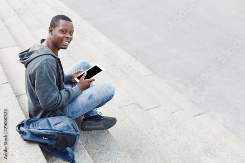 African-american student with tablet on steps