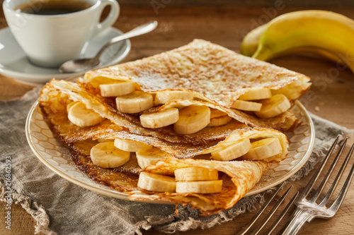 Tasty fresh banana pancakes or wraps with coffee