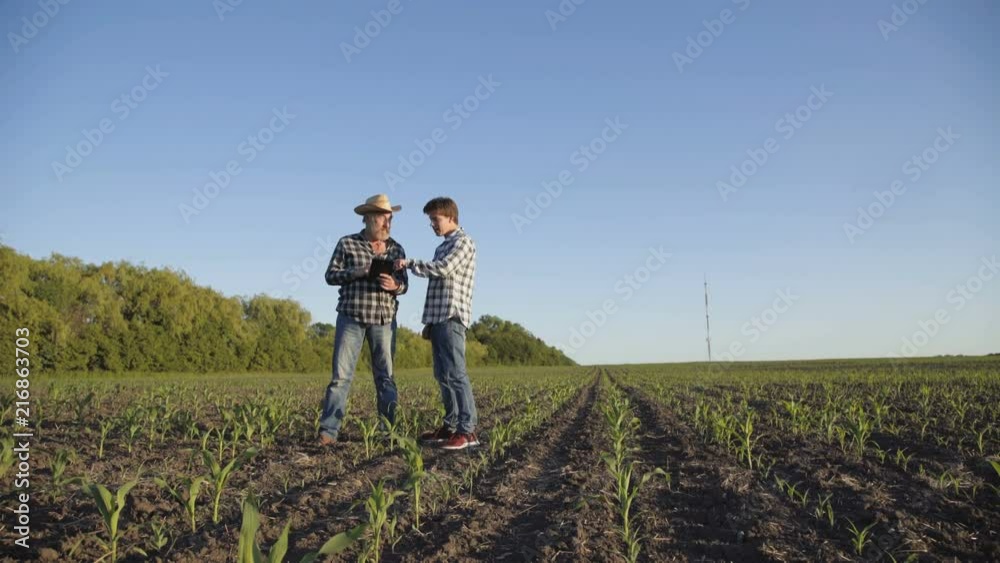 The farmer explains his son about farmland management with smile The farmer explains his son about farmland management with smile