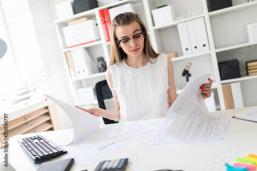 A young girl in the office looks through documents.