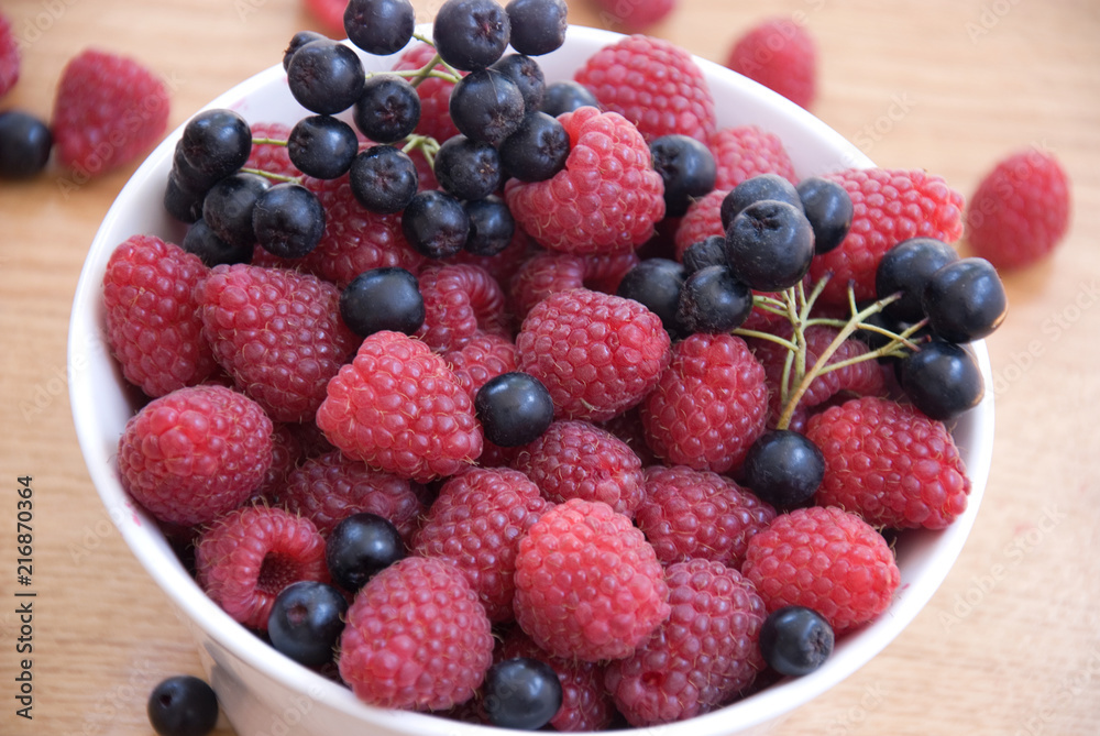 raspberry and aronia in bowl on the table raspberry and aronia in bowl on the table