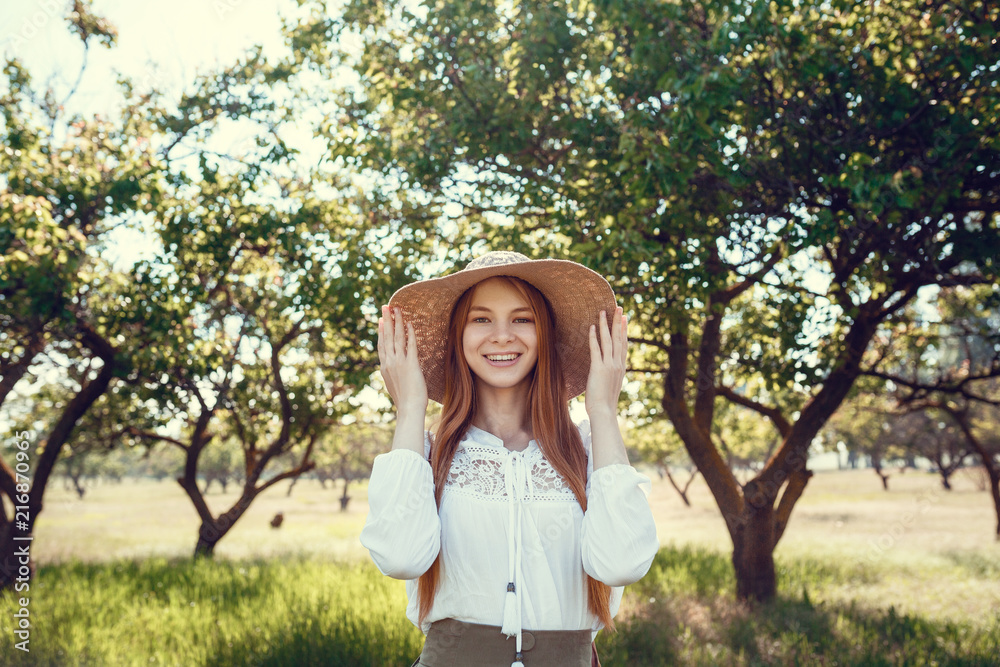 young girl in a straw hat travels green meadows