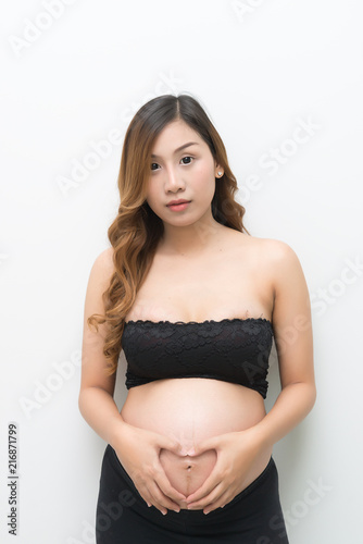 pregnant woman in white dress touch on her belly on white background,asian woman make hand shape heart