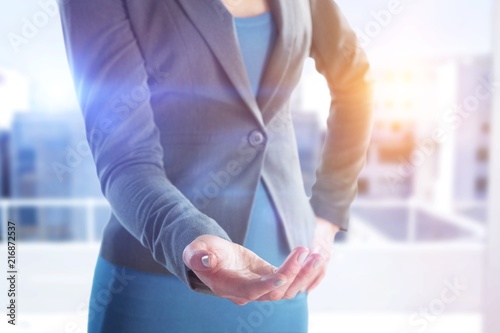 Composite image of mid section of businesswoman with hand on hip