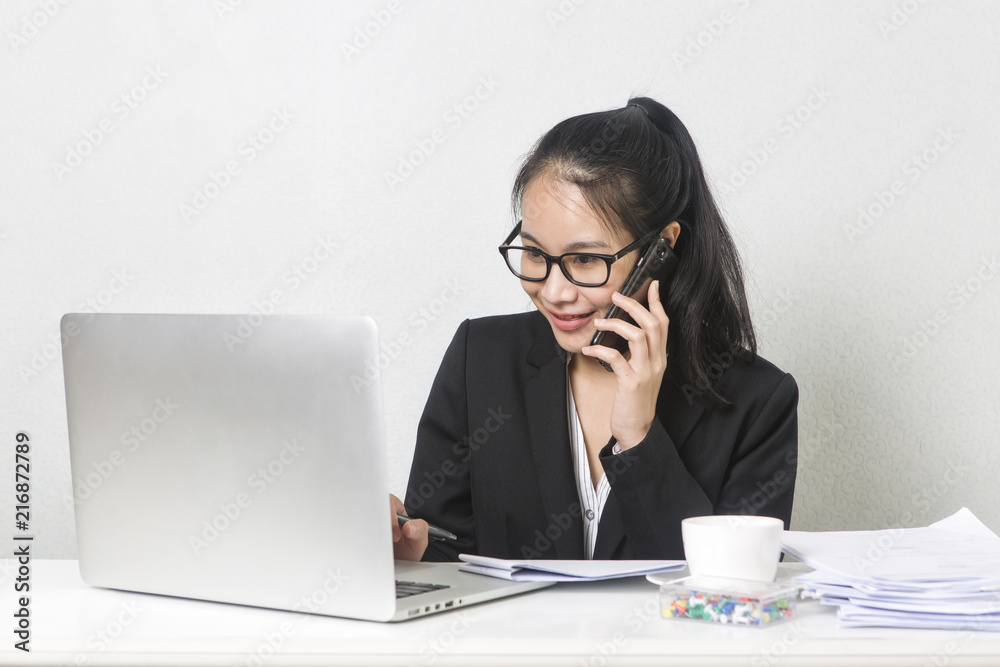Happy business Asian woman working with laptop at white working table, diligent professional working woman.Talking on the phone. Happy business Asian woman working with laptop at white working table, diligent professional working woman.Talking on the phone.