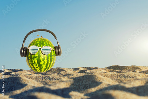 Creative and summer photography of watermelon in the form of a human head with glasses and headphones in the sand on the beach. Concept 