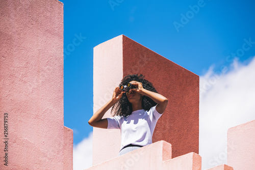 Black woman in a colorful geometric building with a binocular photo