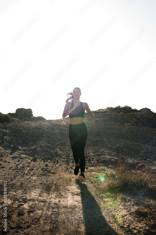 Woman in black running on a sand road